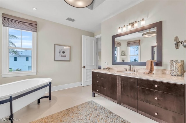 bathroom with baseboards, visible vents, tile patterned floors, vanity, and a freestanding tub