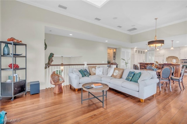 living room featuring recessed lighting, visible vents, ornamental molding, light wood-style flooring, and a notable chandelier