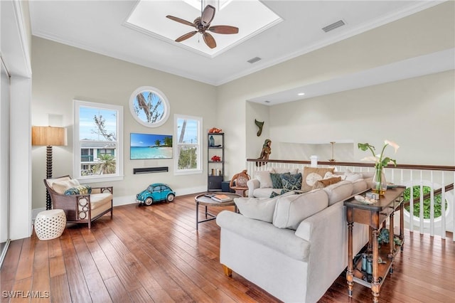 living area featuring a ceiling fan, visible vents, crown molding, and wood finished floors