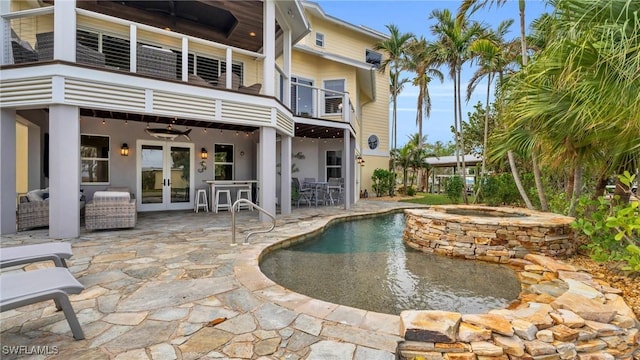 outdoor pool with french doors, a patio, an in ground hot tub, and a ceiling fan