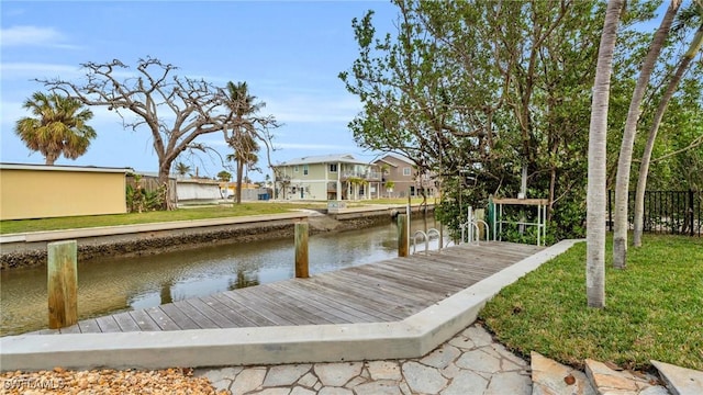 view of dock featuring a water view and a yard