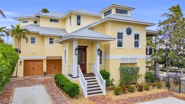 view of front of property with decorative driveway, fence, an attached garage, and stucco siding