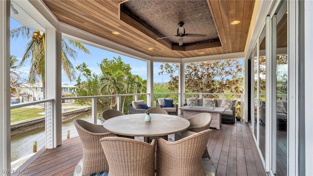 sunroom / solarium with wood ceiling, a tray ceiling, and ceiling fan