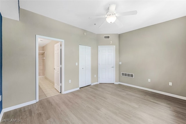 unfurnished bedroom featuring ensuite bathroom, ceiling fan, and light wood-type flooring