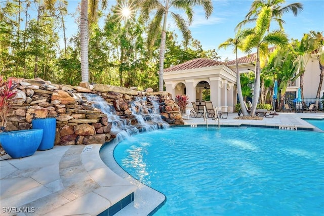 pool featuring a patio area, an outbuilding, and a storage structure