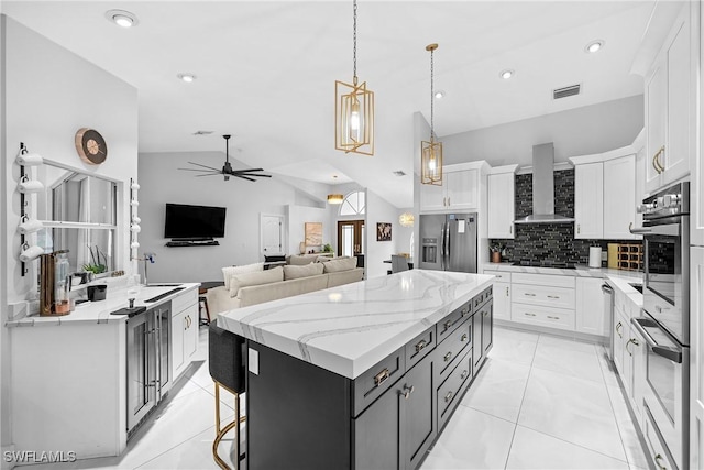 kitchen with decorative light fixtures, wall chimney exhaust hood, white cabinetry, and stainless steel refrigerator with ice dispenser