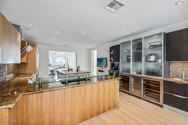 kitchen featuring light hardwood / wood-style floors, wine cooler, sink, tasteful backsplash, and light stone countertops