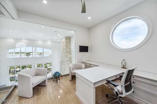 office with ceiling fan, a water view, and light hardwood / wood-style floors