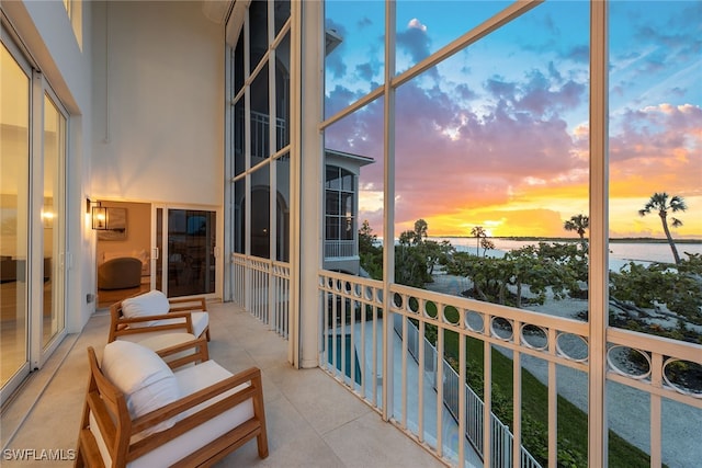 balcony at dusk featuring a water view