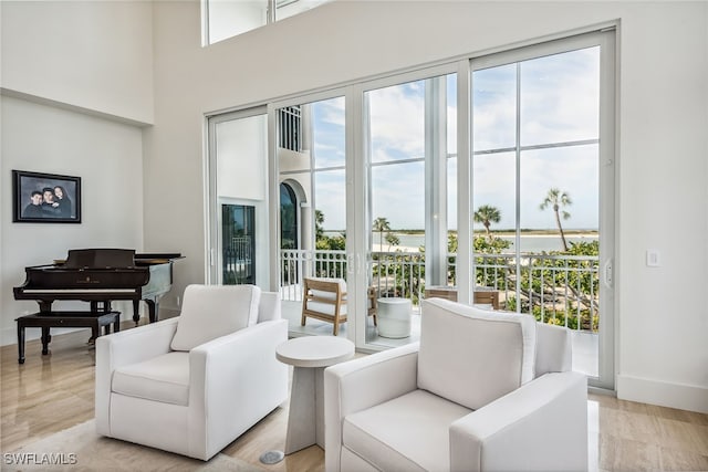 interior space with light hardwood / wood-style flooring, a water view, a healthy amount of sunlight, and a high ceiling