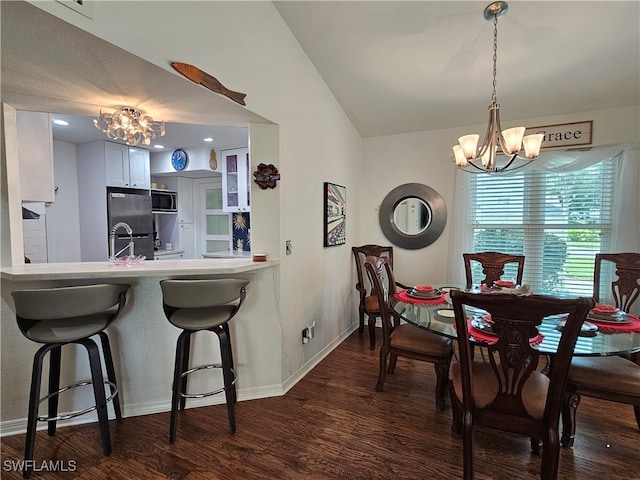 kitchen with kitchen peninsula, appliances with stainless steel finishes, lofted ceiling, white cabinets, and dark wood-type flooring