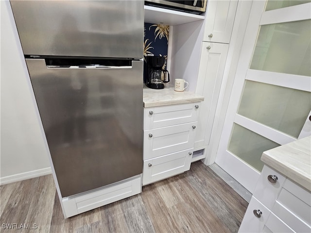 details featuring light wood-type flooring, white cabinets, and stainless steel appliances