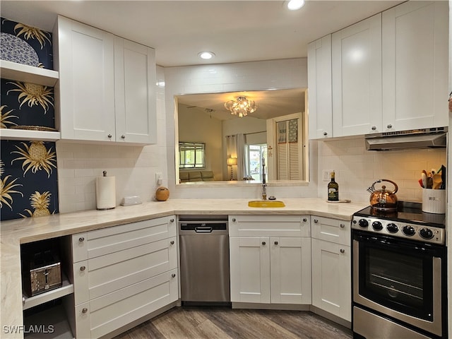 kitchen with white cabinetry, appliances with stainless steel finishes, decorative backsplash, sink, and light hardwood / wood-style flooring