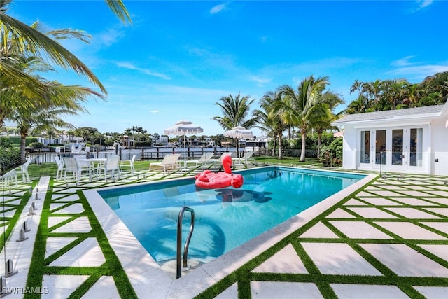 view of pool featuring a patio area, a water view, and french doors