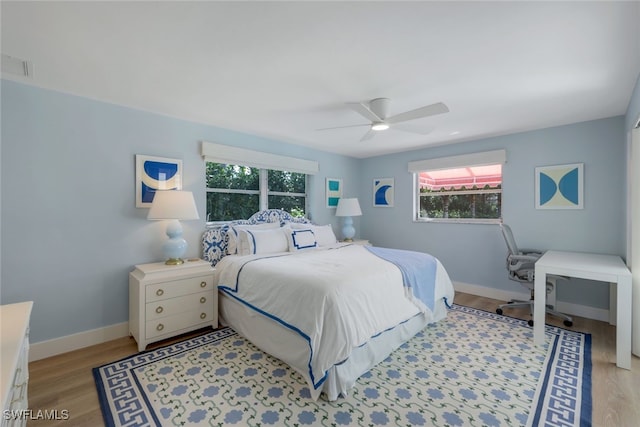 bedroom with ceiling fan, multiple windows, and light wood-type flooring