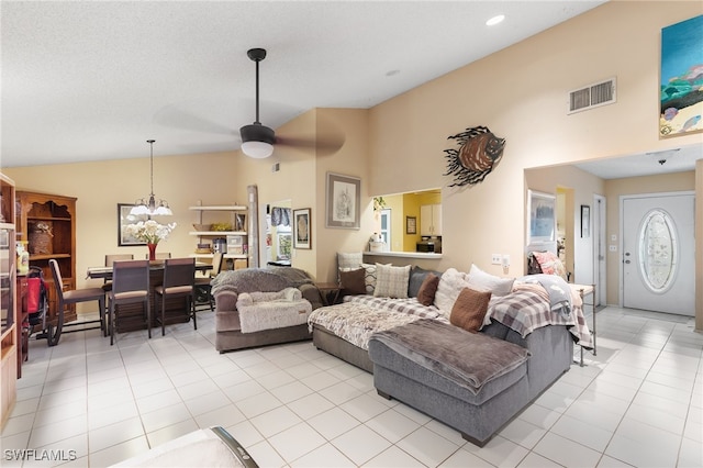 tiled living room with high vaulted ceiling and ceiling fan with notable chandelier