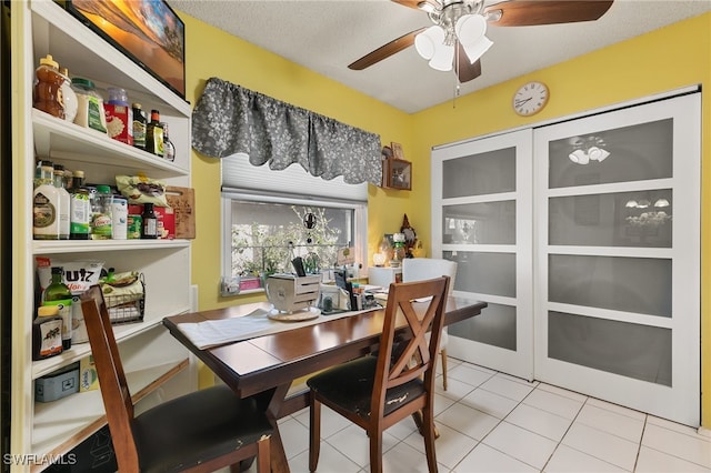 tiled dining room with a textured ceiling and ceiling fan