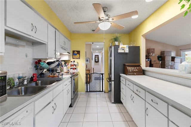 kitchen featuring stainless steel appliances, white cabinetry, a textured ceiling, light tile patterned floors, and sink