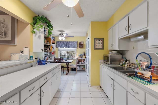 kitchen featuring tasteful backsplash, a textured ceiling, light tile patterned floors, white cabinets, and dishwasher