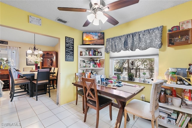 tiled dining space featuring ceiling fan with notable chandelier and a textured ceiling