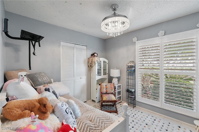 bedroom with an inviting chandelier, a textured ceiling, and a closet