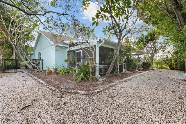 120 Sand Hill St, Marco Island, FL 34145 - view of home's exterior featuring a sunroom, a gate, and stucco siding