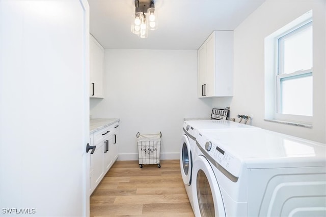 laundry area featuring washing machine and dryer, cabinets, and light hardwood / wood-style flooring