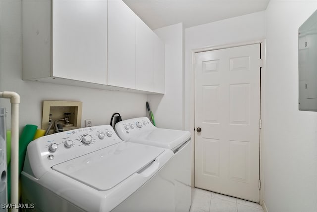 washroom featuring electric panel, washing machine and dryer, cabinets, and light tile patterned floors