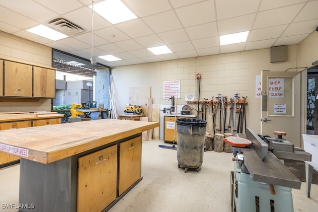 kitchen with butcher block counters, a center island, and a drop ceiling