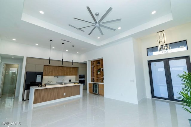 kitchen featuring a large island, decorative light fixtures, sink, and a tray ceiling