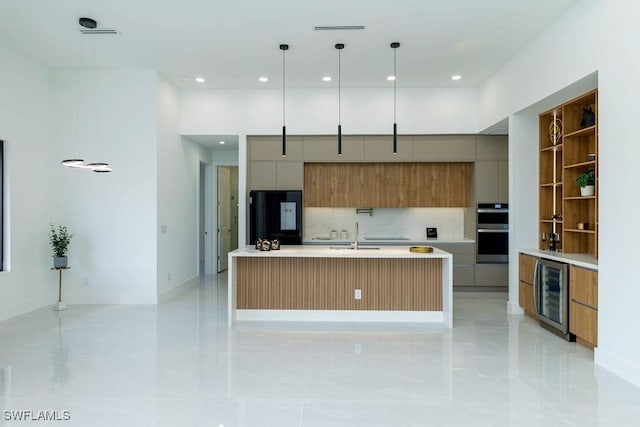 kitchen featuring pendant lighting, black refrigerator, an island with sink, double oven, and beverage cooler