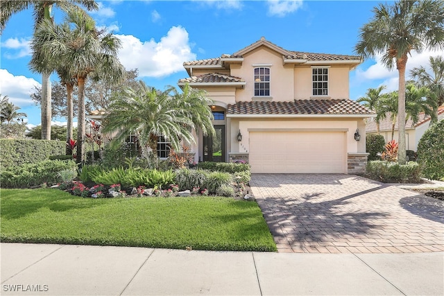 mediterranean / spanish home featuring a garage and a front yard