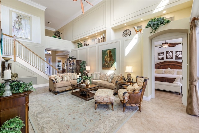 living room featuring a high ceiling, ceiling fan, and ornamental molding