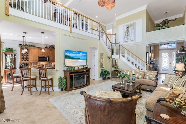 living room with a towering ceiling and ornamental molding