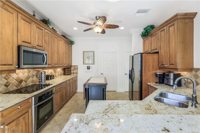 kitchen featuring ornamental molding, stainless steel appliances, sink, and light stone countertops