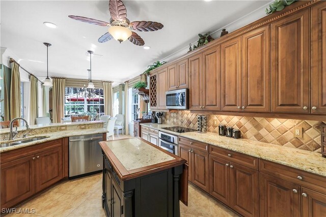 kitchen with stainless steel appliances, sink, light stone countertops, light tile patterned floors, and a center island