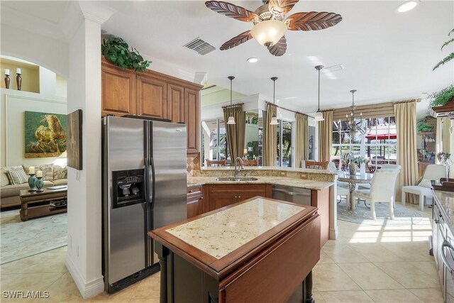 kitchen featuring stainless steel appliances, a kitchen island, decorative light fixtures, light tile patterned floors, and sink