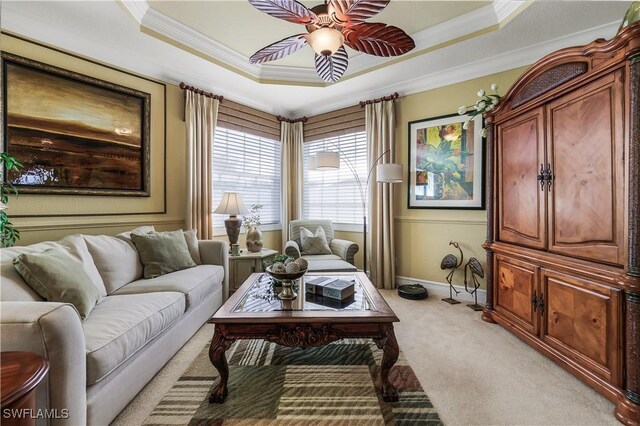 living area featuring ceiling fan, light carpet, crown molding, and a tray ceiling