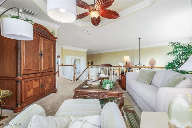 carpeted living room featuring ceiling fan, a raised ceiling, and crown molding