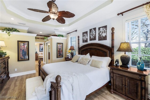 bedroom with ornamental molding, hardwood / wood-style floors, ceiling fan, and a raised ceiling