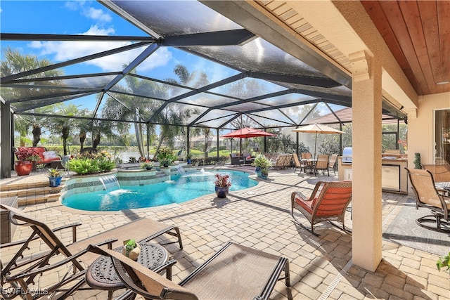 view of swimming pool featuring a patio, glass enclosure, pool water feature, and exterior kitchen