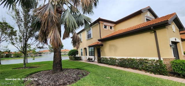 view of side of home featuring a water view and a yard