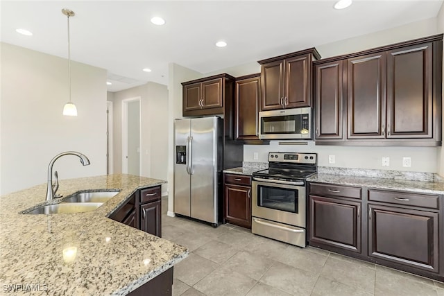 kitchen with dark brown cabinetry, sink, appliances with stainless steel finishes, light stone countertops, and pendant lighting