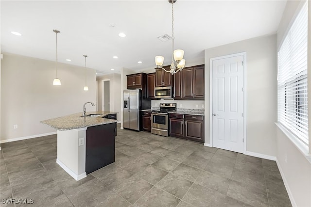 kitchen featuring light stone counters, appliances with stainless steel finishes, pendant lighting, an island with sink, and a chandelier