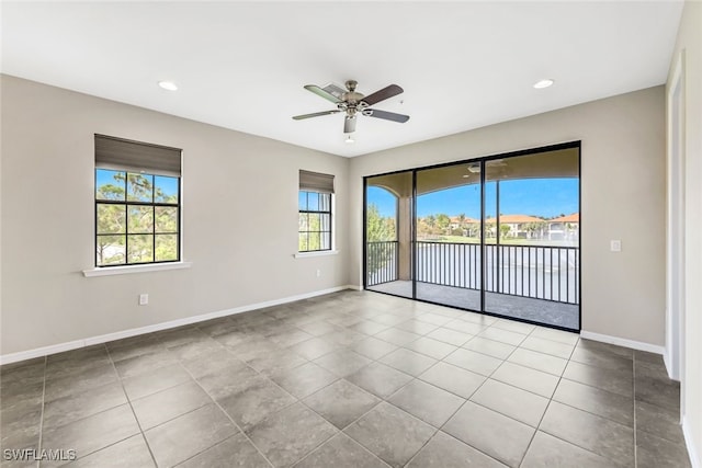 tiled empty room with ceiling fan and plenty of natural light