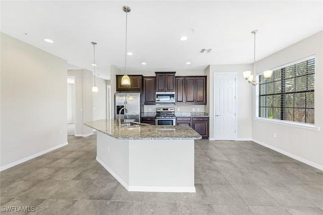 kitchen with a kitchen island with sink, sink, pendant lighting, and appliances with stainless steel finishes