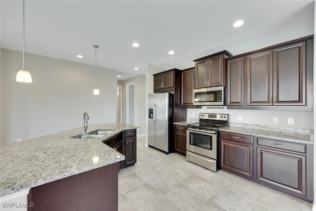 kitchen featuring dark brown cabinetry, appliances with stainless steel finishes, light stone counters, a sink, and recessed lighting