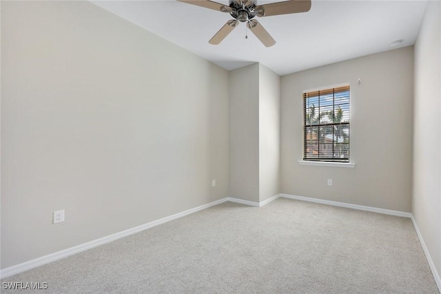 spare room with light carpet, ceiling fan, and baseboards