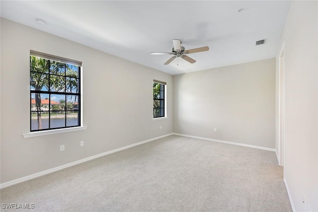 unfurnished room with carpet floors, a wealth of natural light, visible vents, and baseboards