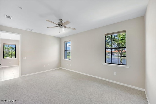 spare room with carpet floors, visible vents, ceiling fan, and baseboards